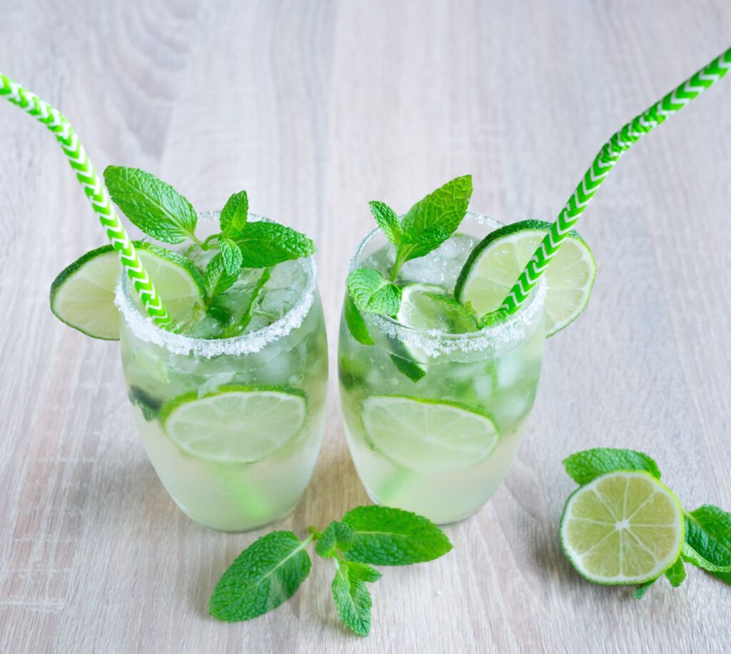 Two glasses of virgin mojito with lime slices, fresh mint and green straws